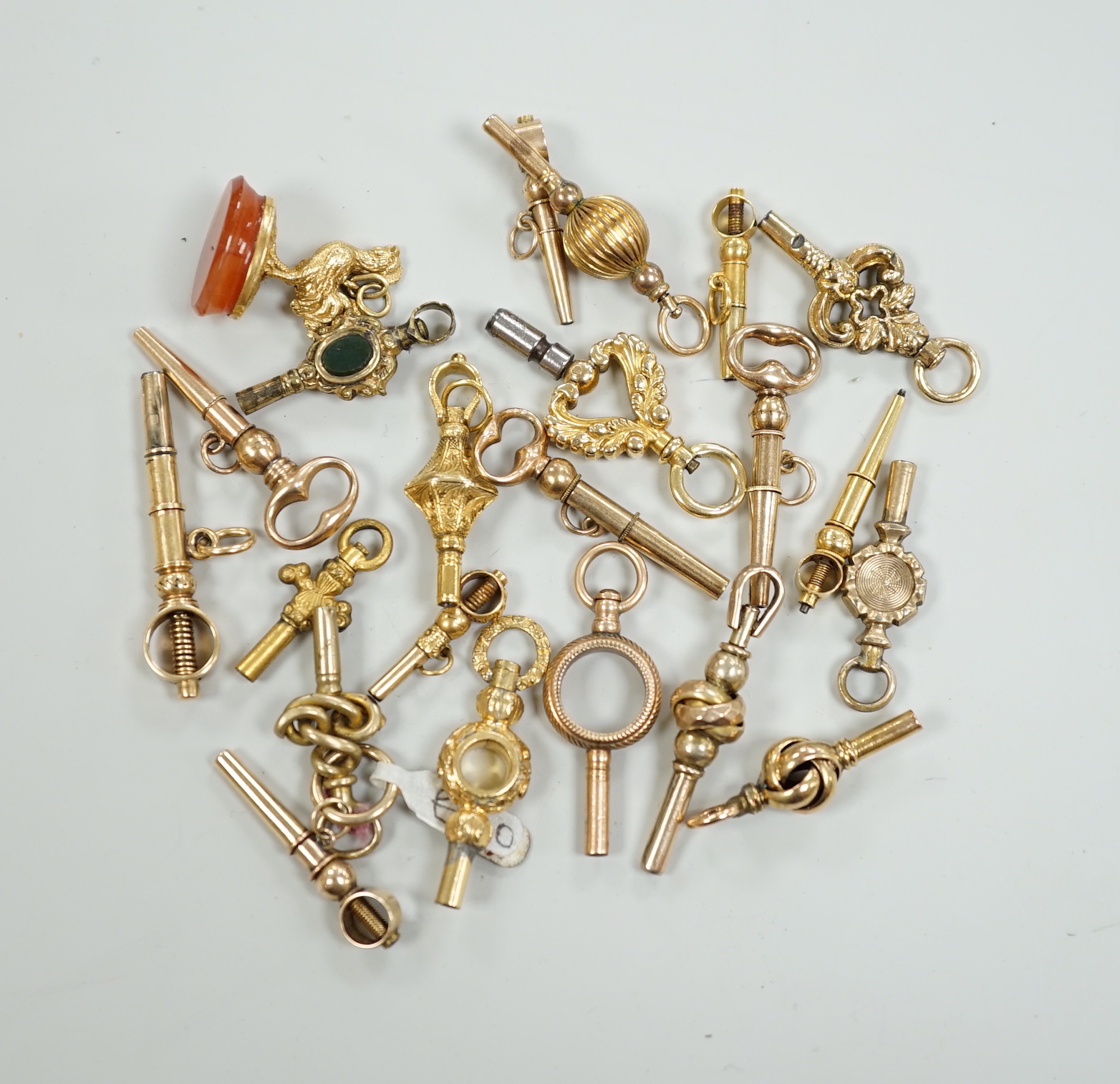 Twenty assorted mainly 19th century yellow metal small watch keys, including trade insignia, bloodstone set and keys to be turned in one direction, largest 37mm, together with a 19th century yellow metal overlaid and aga